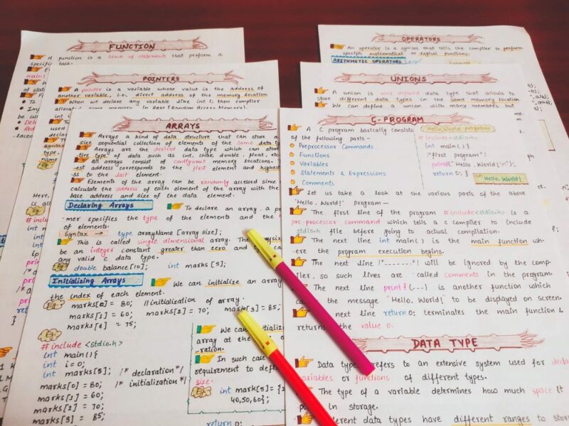 c programming first page with headings of array, union, pointer, function, operators in sample 5 with pink Highlighters include in photo of physical copy kept on wooden desk